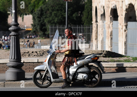 Un soldato romano seduto su un ciclomotore al di fuori il Colosseo a Roma, Italia. Il Colosseo è in costruzione. Foto Stock