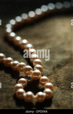 Un singolo filamento di perle su un vellutato brocade. Foto Stock