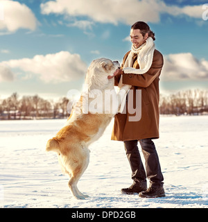 Uomo e dell Asia centrale pastore giocando con il suo cane all'aperto Foto Stock