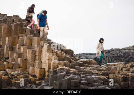 I visitatori a piedi e salire su pile di colonne di basalto che compongono la famosa in tutto il mondo Giants Causeway nella contea di Antrim. Foto Stock