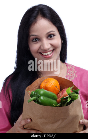 Felice giovane donna indiana holding sacchetto shopper con pieno di frutta e verdura Foto Stock