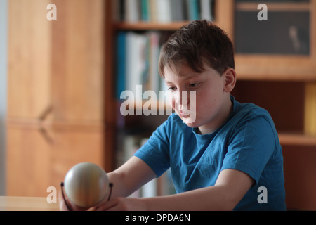 Ragazzo alla ricerca di qualcosa su una sfera del mondo Foto Stock