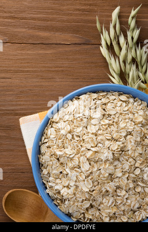 Fiocchi di avena in un recipiente su sfondo di legno Foto Stock