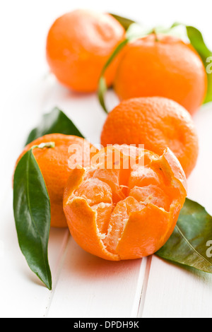Mandarini freschi con foglie di colore verde su bianco sullo sfondo di legno Foto Stock