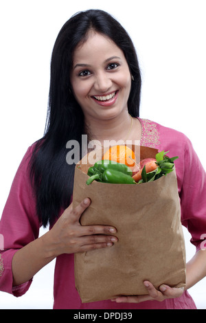 Giovane donna indiana holding sacchetto shopper con pieno di frutta e verdura Foto Stock