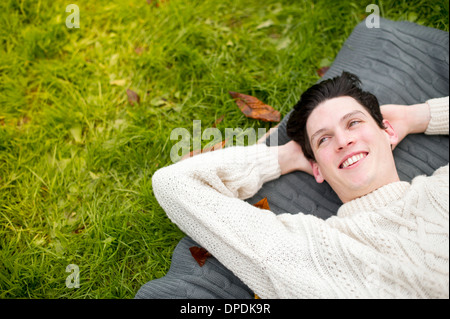 Giovane uomo disteso sul tappeto che indossa un maglione Foto Stock