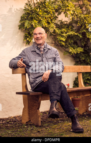 Senior uomo seduto su un banco di lavoro Foto Stock