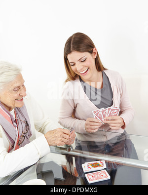 Felice donna senior giocando a carte con sorridente nipote a casa Foto Stock