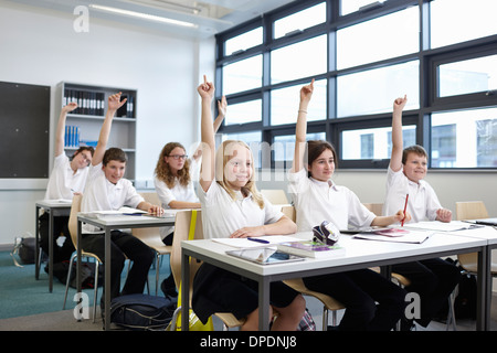 Un gruppo di scolari con le mani sollevate in aula