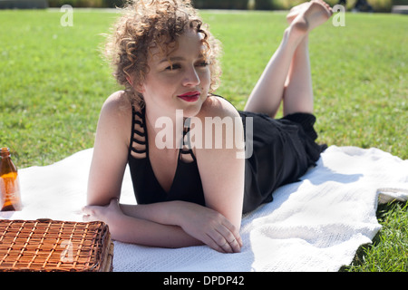 Giovane donna sdraiata sulla coperta picnic nel parco Foto Stock