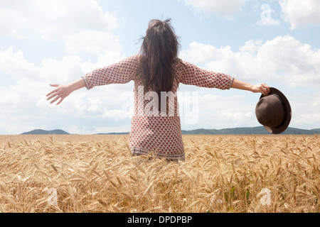 Metà donna adulta in piedi nel campo di grano con bracci di ampio Foto Stock