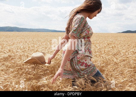 Mid adult woman walking through wheat field Foto Stock