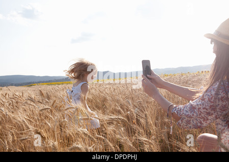 Madre fotografare la ragazza che corre attraverso il campo di grano Foto Stock