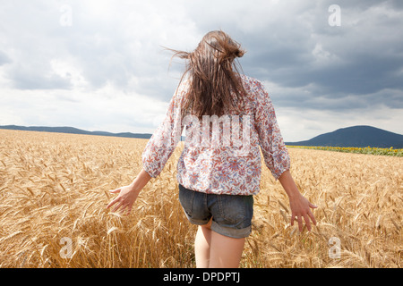 Metà donna adulta a piedi attraverso il campo di grano Foto Stock