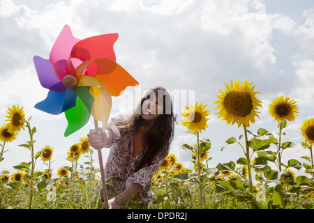 Donna che mantiene il mulino a vento in un campo di girasoli Foto Stock