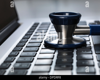 Uno stetoscopio seduta su laptop che illustra online sanitario e medico alla scrivania Foto Stock