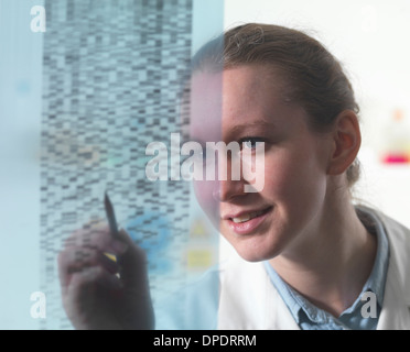 Ricercatore femmina esaminando autoradiogramma di DNA su gel in laboratorio Foto Stock