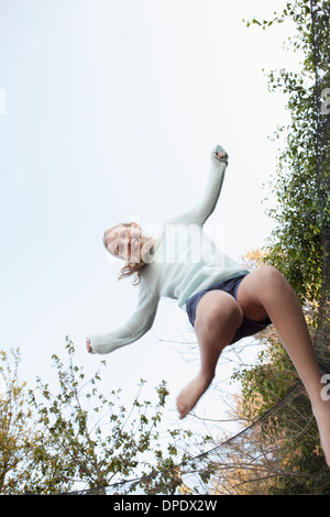 Ragazza jumping metà aria sul trampolino da giardino Foto Stock
