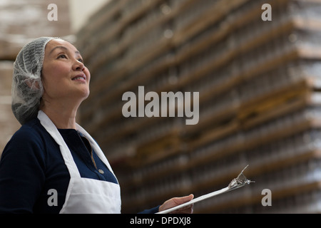 Operaio di fabbrica con appunti in magazzino Foto Stock