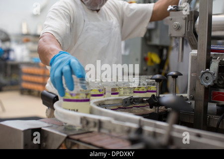 L'uomo la manipolazione dei vasetti di vetro sulla linea di produzione Foto Stock