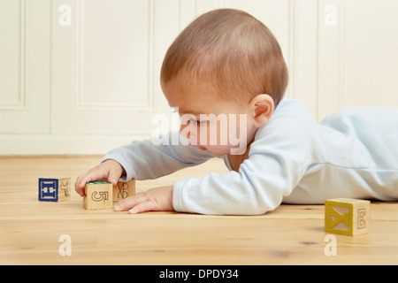 Il bambino che giace sulla parte anteriore a giocare con i blocchi di costruzione Foto Stock