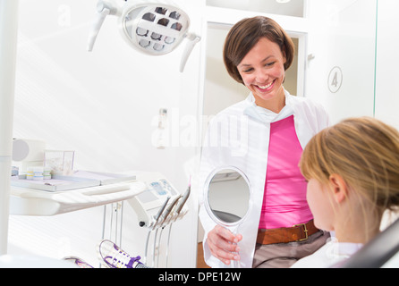 Dentista tenendo la mano specchio nella parte anteriore della faccia di ragazze Foto Stock