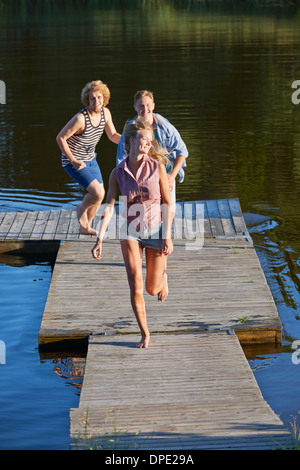 Tre giovani amici adulti in esecuzione sul molo, Gavle, Svezia Foto Stock