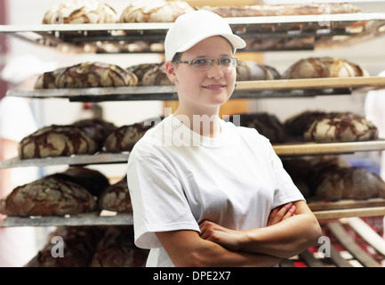 Baker in piedi nella parte anteriore del pane su ripiani con le braccia incrociate Foto Stock