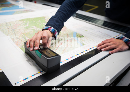 Lavoratore verificare la qualità di stampa dei prodotti nel laboratorio di stampa Foto Stock