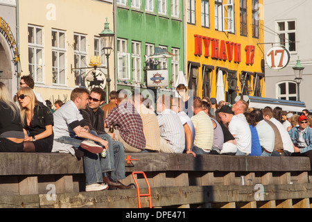 La folla seduti sulla banchina a Nyhavn in una serata estiva, Copenhagen, Danimarca Foto Stock