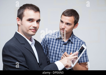 Due imprenditori con tavoletta digitale in ufficio. Foto Stock