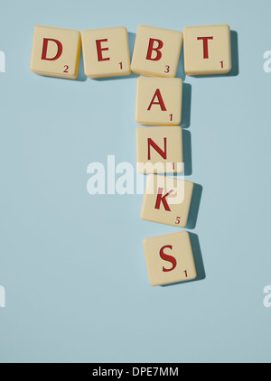Scrabble pezzi disposto per scandire le parole di debito e le banche su uno sfondo blu Foto Stock