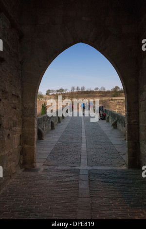 Pellegrini in cammino il Camino de Santiago attraversare il ponte medievale a Puente La Reina, sul Camino di Santiago de Compostela. Foto Stock