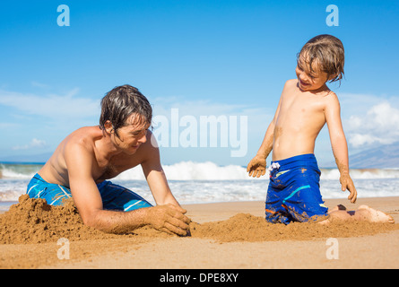 Il padre e il Figlio insieme giocando nella sabbia sulla spiaggia tropicale, costruire castelli di sabbia Foto Stock