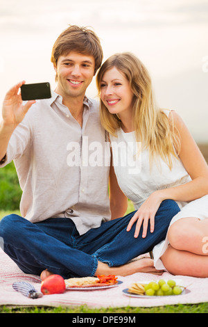 Giovane tenendo Selfie con telefono cellulare all'aperto Foto Stock