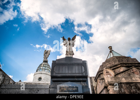 BUENOS AIRES, Argentina — una statua d'angelo incorona il mausoleo cortese Guglielmone nel cimitero di Recoleta (Cementerio de la Recoleta). Questo elemento scultoreo rappresenta un motivo comune nell'arte funeraria del XIX secolo, dove gli angeli spesso simboleggiano la protezione e la guida divina. La statua esemplifica le elaborate sculture commemorative che caratterizzano il patrimonio architettonico di questo cimitero storico. Foto Stock