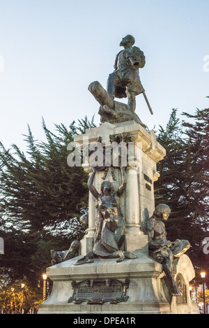 Ferdinand Magellan Monument Plaza De Armas Punta Arenas Cile // PUNTA ARENAS, Cile — Un monumento dedicato a Ferdinando Magellano, l'esploratore portoghese che ha guidato la prima spedizione per circumnavigare il globo, si trova in primo piano in Plaza de Armas, la piazza principale di Punta Arenas. La statua onora il viaggio storico di Magellano del 1519-1522, anche se Magellano stesso morì durante il viaggio nelle Filippine. Punta Arenas, fondata nel 1848, è la capitale della regione più meridionale del Cile, Magallanes e Antártica Chilena. La città ha la particolarità di essere il più grande cen urbano Foto Stock