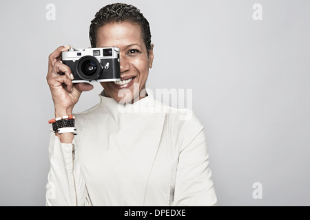 Ritratto in studio di Felice donna matura mantenendo la fotocamera Foto Stock