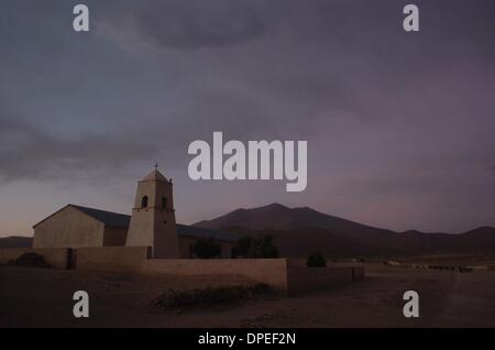 Dic 02, 2006 - Uyuni, Bolivia - giovani bambini allevamento le loro famiglie llama torna a una partecipazione a penna dopo una giornata di pascolo nei campi accanto alla città la chiesa cattolica nelle alte pianure del sud della Bolivia. Mentre la Bolivia è 30 percento indigeni Quechua, 95 percento dei nove milioni di abitanti sono cattolici romani. Il resto sono metodista evangelica. Sessantaquattro per cento di Bol Foto Stock