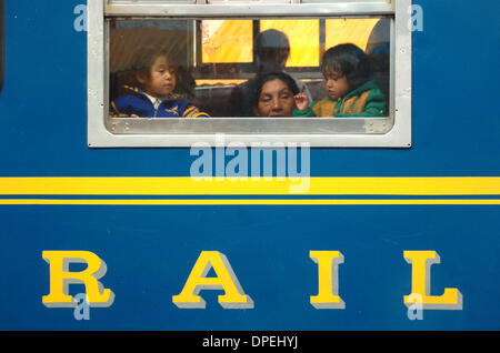 26 nov 2006 - Aguas Calientes, Perù - una donna e due bambini piccoli peer al di fuori della finestra di un treno passeggeri arrestato nella cittadina turistica di Aguas Calientes, nominato dopo le sorgenti calde che vi si trovano. I peruviani sono su un treno locale che è meno costoso di quello preso dai turisti per raggiungere la città, che si trova a soli 30 minuti di autobus per le rovine Inca di Machu Picchu. Un Foto Stock