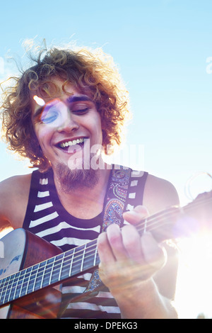 Giovane uomo a suonare la chitarra nella luce del sole Foto Stock