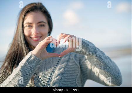 Giovane donna messa a forma di cuore con le mani Foto Stock