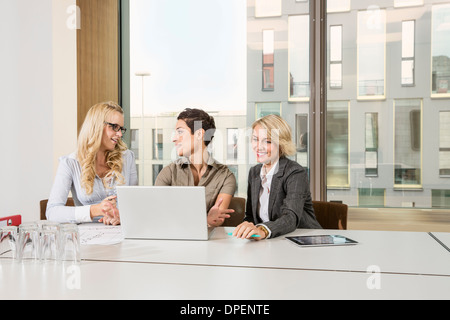 Imprenditrici seduti ad un tavolo per conferenza utilizzando laptop Foto Stock