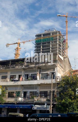 Grande e alto di statura gru utilizzate per costruire grattacieli torreggia su un sito in costruzione su una strada di città in Phnom Penh Cambogia. Foto Stock