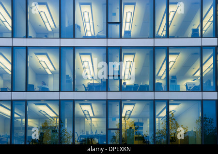 Facciata di un ufficio moderno edificio con luci accese in uffici di sera, Monaco di Baviera, Germania Foto Stock