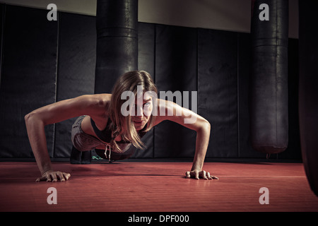 Donna facendo spingere ups in palestra Foto Stock