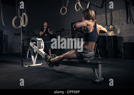 Donna che utilizza vogatore in palestra Foto Stock