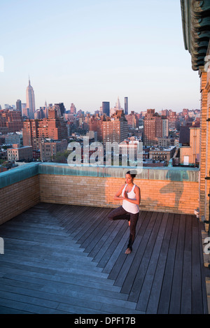 La donna a praticare yoga sul tetto Foto Stock