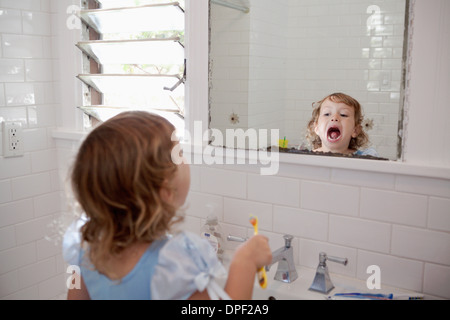 Toddler femmina cercando in mirror la pulizia dei denti Foto Stock