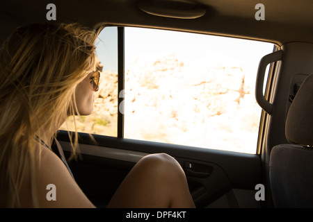 Giovane donna che guarda fuori del sedile posteriore nella finestra auto, Joshua Tree National Park, California, Stati Uniti d'America Foto Stock